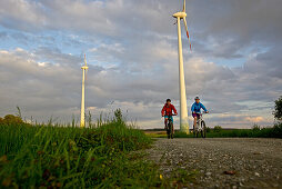 Two cyclists riding electric bicycles between fields, Tanna, Thuringia, Germany