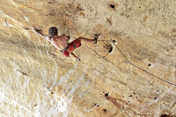 Junger Mann klettert eine Felswand hinauf, Finale Ligure, Savona, Italien