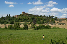 Woman nordic walking through a field at the foot of the Vinery Palazzo Massani, near San Quirico d'Orcia, Toskana, Italy, Europe