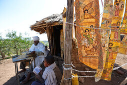 Priester Sine Tebeb vor einer Hütte, Ziegenhäute mit biblische Szenen in Geez, bei Bet Giyorgis, St.-Georgs-Kirche, Lalibela, Amhara, Äthiopien