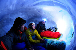 Three mountaineers bivouacking in a snow cave at Collado Este, Monte Sarmiento, Cordillera Darwin, Tierra del Fuego, Chile