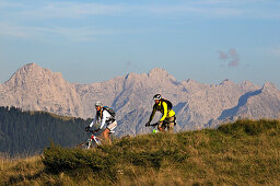 Mountain bikers passing Winklmoosalm, Berchtesgaden Alps in background, Chiemgau, Upper Bavaria, Germany