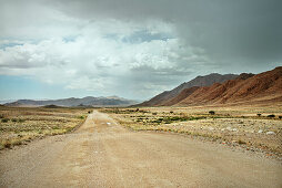 Dusty road after heavy rainfall with puddles, Tiras Mountain Range, Namib Naukluft National Park, Namibia, Africa