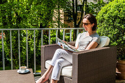 Woman reading a magazine on a balcony, Hamburg, Germany