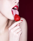 Woman licking strawberry