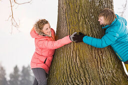 Mid adult couple hugging tree