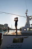 Woman on yacht, using binoculars