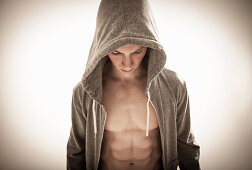 Man in hoodie with muscular body looking down