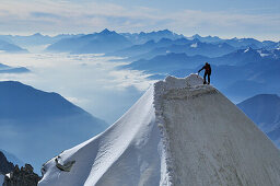 Mountaineer climbing a cornice on the ridge of Tour Ronde, Mont Maudit, Mont Blanc Group, France