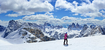Frau auf Skitour steigt zum Hochebenkofel auf, Dreischusterspitze, Zwölferkofel, Drei Zinnen und Schwalbenkofel im Hintergrund, Sextener Dolomiten, Südtirol, Italien