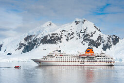 Expedition cruise ship MS Hanseatic (Hapag-Lloyd Cruises) and ice covered mountains, Lemaire Channel, near Graham Land, Antarctica