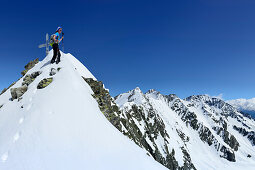 Female back-country skier at summit of Fuenfte Hornspitze, Zillertal Alps, Ahrntal, South Tyrol, Italy