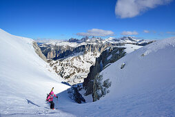 Frau auf Skitour steigt durch enges Couloir im Val Culea auf, Geisler im Hintergrund, Sella, Sellagruppe, Dolomiten, Südtirol, Italien