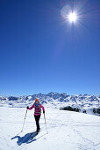 Female back-country skier ascending to Piz Lagrev, Bernina Range in background, Oberhalbstein Alps, Engadin, Canton of Graubuenden, Switzerland