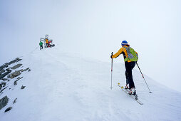 Frau auf Skitour steigt zum Gipfelkreuz des Hohen Weißzint auf, Zillertaler Alpen, Südtirol, Italien