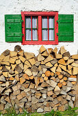 Holzscheite unter einem Fenster einer Almhütte, Spitzstein, Chiemgauer Alpen, Tirol, Österreich
