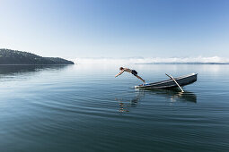 Man swimming in lake Starnberg, the Alps with mount Zugspitze in early morning fog, Berg, Upper Bavaria, Germany