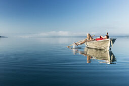 Man in a rowboat on lake Starnberg, the Alps and mount Zugspitze in early morning fog, Berg, Upper Bavaria, Germany