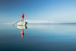 Man in a rowboat on lake Starnberg, the Alps and mount Zugspitze in early morning fog, Berg, Upper Bavaria, Germany