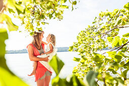 Mother carrying daughter in her arms, lake Starnberg, Berg, Upper Bavaria, Germany