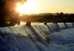 Angler auf dem Wehr der Parry Creek Road über den Ord River bei Sonnenuntergang, nahe Kununurra, Western Australia, Australien