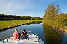 Zwei Frauen sitzen auf dem Bug eines Hausboots und quatschen vertieft, Grosser Zechliner See, Nordbrandenburger Seenplatte (unmittelbar angrenzend an die Mecklenburgische Seenplatte), Brandenburg, Deutschland, Europa