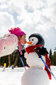 Mädchen küsst einen Schneemann auf Karottennase, Kreischberg, Murau, Steiermark, Österreich