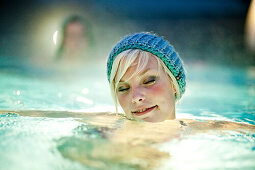 Junge Frau mit Strickmütze badet in einem Thermalbad, Bad Radkersburg, Steiermark, Österreich