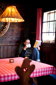 Woman drinking a cup of tea while reading a book, Styria, Austria