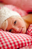 Junge Frau mit Mütze liegt im Bett