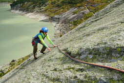 Woman climbing on granite slab, lake in background, Raeterichsboden, Grimsel pass, Bernese Oberland, Switzerland