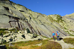 Zwei Personen mit Kletterausrüstung gehen auf Kletterfelsen zu, Azalee Beach, Grimselpass, Berner Oberland, Schweiz