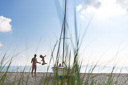 Father and two children (1-4 years) playing on a sailboat at Baltic Sea beach, Marielyst, Falster, Denmark