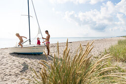 Father and two children (1-4 years) playing on a sailboat at Baltic Sea beach, Marielyst, Falster, Denmark