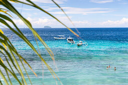 Urlauber baden im Meer, Fischerboote im Hintergrund, Blaue Lagune, Padang Bai, Bali, Indonesien