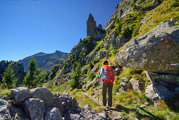 Frau wandert auf Weg auf Felsturm zu, Trans-Lagorai, Lagorai-Höhenweg, Lagorai, Dolomiten, UNESCO Welterbe Dolomiten, Trentino, Italien
