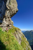 Frau wandert auf versichertem Steig unter Felsüberhang hindurch, Trans-Lagorai, Lagorai-Höhenweg, Lagorai, Dolomiten, UNESCO Welterbe Dolomiten, Trentino, Italien