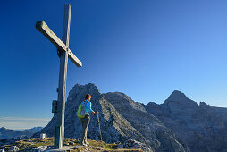 Woman reaching the summit cross on Ulrichshorn while hiking, Nurracher Hoehenweg, Ulrichshorn, Loferer Steinberge range, Tyrol, Austria