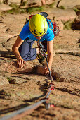 Woman climbing on red Granite rock, Mottarone, Piedmont, Italy