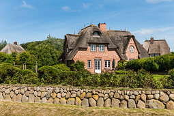 Thatched-roof house surrounded by natural stone wall, Sylt, Schleswig-Holstein, Germany