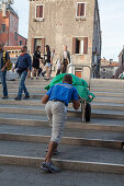 Arbeiter mit Sackkarre, Transport und Entladen, Transport von Hotelwäsche über die Treppen der Brücken, Venedig, Italien