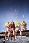 Girls with dip nets sitting on jetty at lake Starnberg, Upper Bavaria, Bavaria, Germany