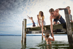 Parents holding daughter in lake Starnberg, Upper Bavaria, Bavaria, Germany