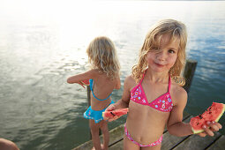 Two girls eating slices of melon, lake Starnberg, Upper Bavaria, Bavaria, Germany