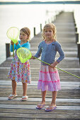 Two girls with a dip nets on a jetty at lake Starnberg, Upper Bavaria, Bavaria, Germany