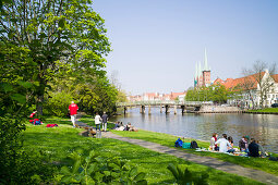 Lawn on river Obertrave with view to historic city, Lubeck, Schleswig-Holstein, Germany