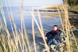 Mann sitzt am Strand, Rankwitz, Halbinsel Lieper Winkel, Usedom, Mecklenburg-Vorpommern, Deutschland