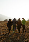 Young people crossing a meadow, Grosser Alpsee, Immenstadt, Bavaria, Germany