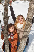 Two young women between tree trunks, Spitzingsee, Upper Bavaria, Germany