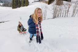 Young woman pulling friend on sled, Spitzingsee, Upper Bavaria, Germany